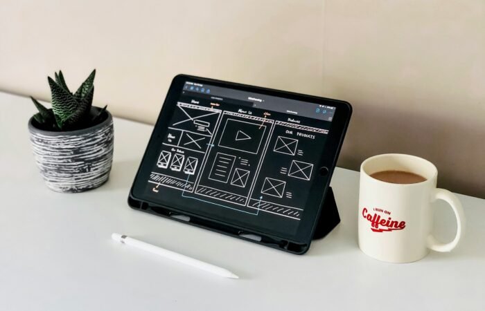 black ipad beside white ceramic mug on white table